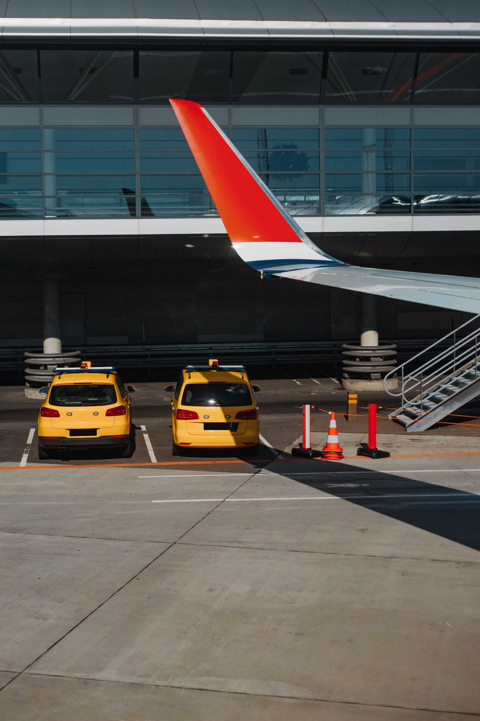 Zwei gelbe Taxis parkten unter einer Flugzeugtragfläche an einem städtischen Flughafen.